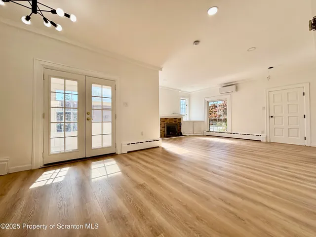 a view of an empty room with window and wooden floor