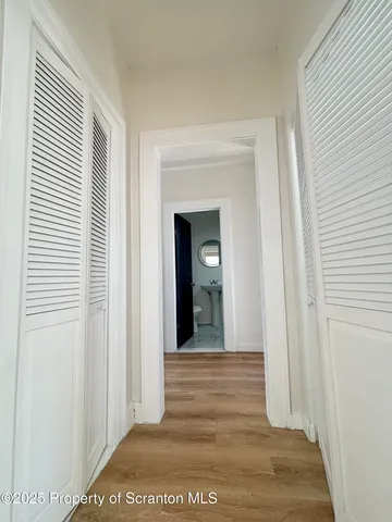 a view of a hallway with wooden floor and a bathroom