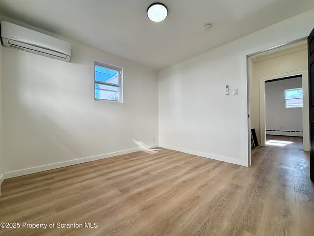 a view of an empty room with wooden floor and closet