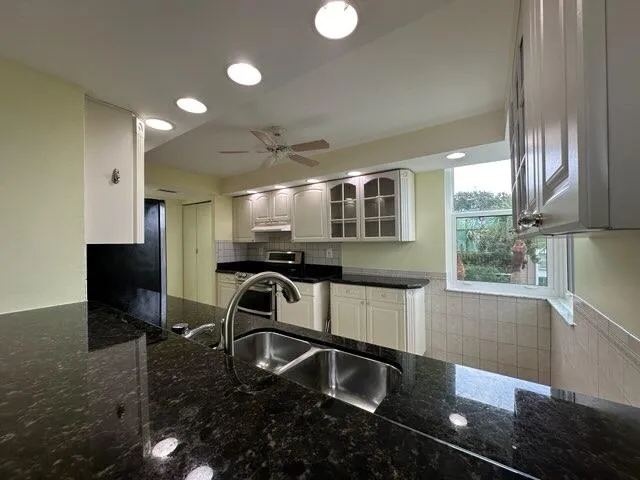 a kitchen with granite countertop a refrigerator a stove and a sink