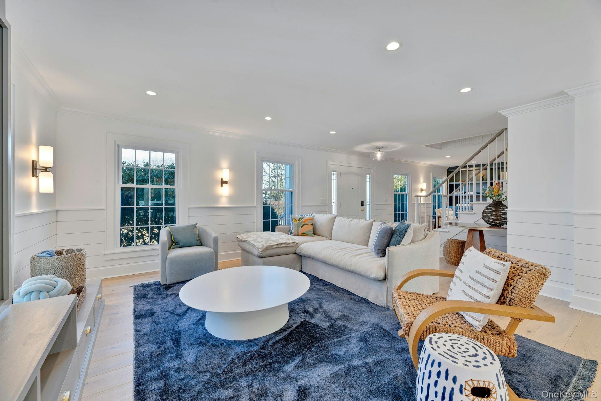 110 Sleepy Hollow Lane Southold, NY 11971 - Photo 5 of 46 Living area with a wainscoted wall, light wood-style floors, recessed lighting, crown molding, and stairs