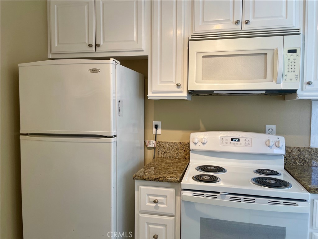 1000 West MacArthur Boulevard, Unit 87 Santa Ana, CA 92707 - Photo 4 of 36 a white refrigerator freezer and a stove sitting inside of a kitchen