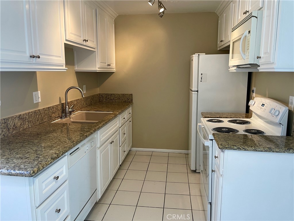 1000 West MacArthur Boulevard, Unit 87 Santa Ana, CA 92707 - Photo 7 of 36 a kitchen with granite countertop a sink stove and cabinets