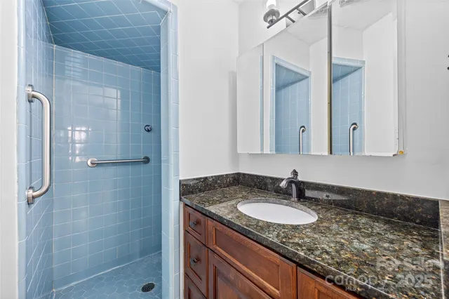 a bathroom with a granite countertop sink a mirror and shower