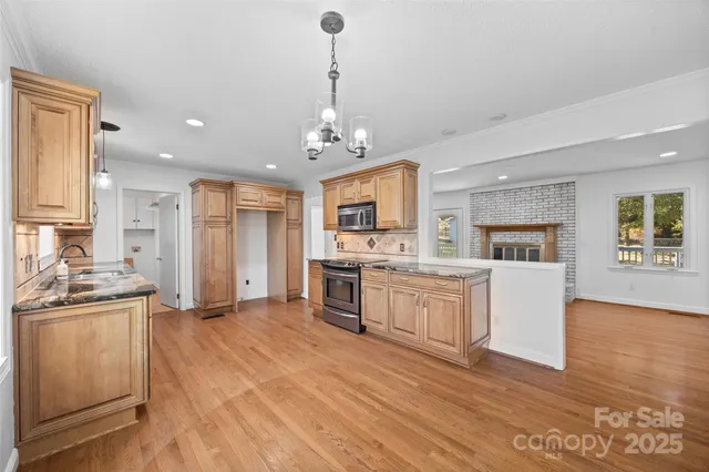 a large kitchen with kitchen island a large counter top space a sink stainless steel appliances and cabinets