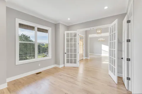a view of empty room with wooden floor and fan