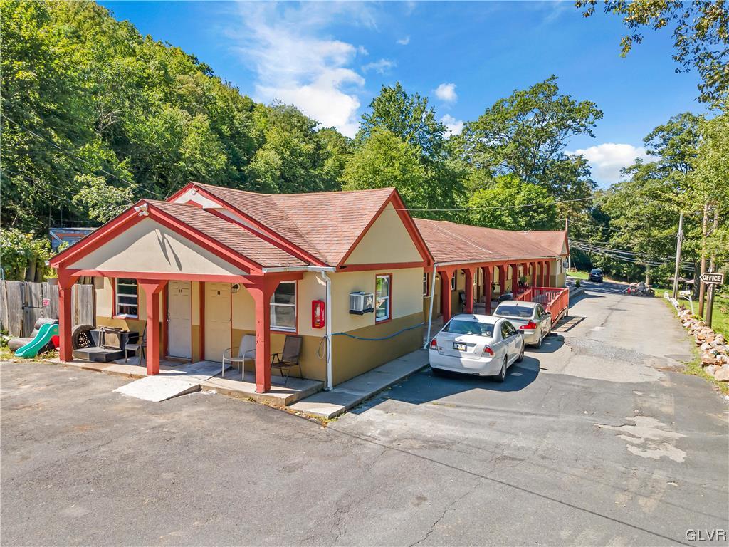 a view of a white house with large outdoor space and a car parked in front of it