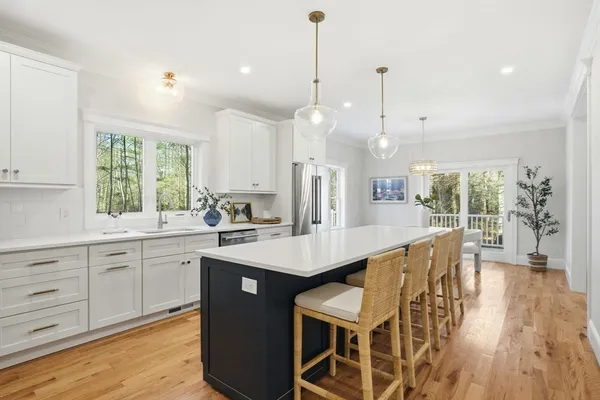 a kitchen with stainless steel appliances granite countertop a dining table chairs refrigerator and sink