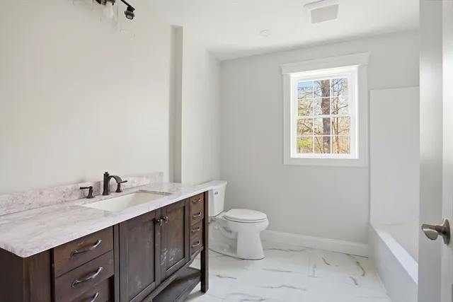 a bathroom with a granite countertop sink a toilet and a window