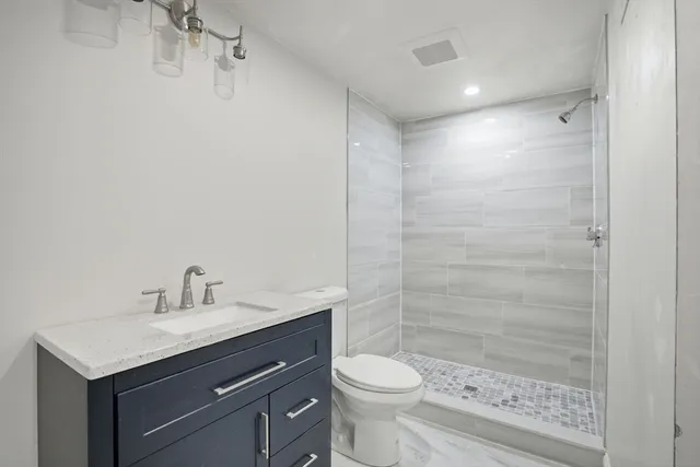 a bathroom with a granite countertop sink a toilet and shower