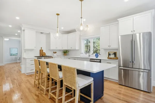a kitchen with stainless steel appliances granite countertop a dining table chairs refrigerator and sink