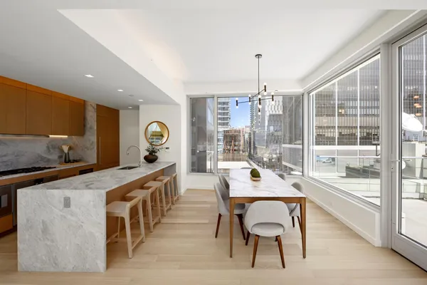 a kitchen with stainless steel appliances granite countertop a stove a sink a dining table and chairs with wooden floor