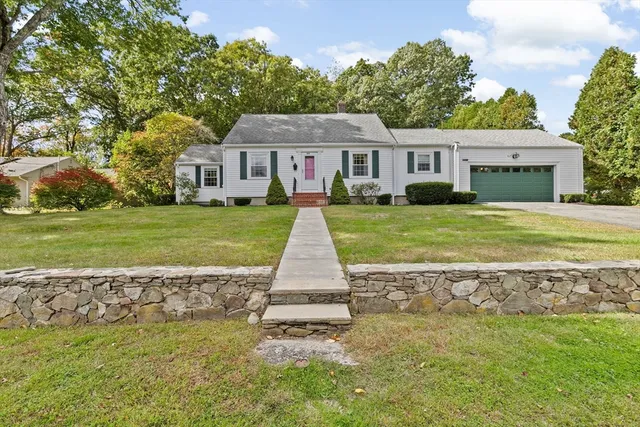 a front view of a house with a garden and trees