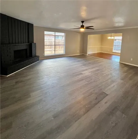 an empty room with wooden floor fireplace and windows