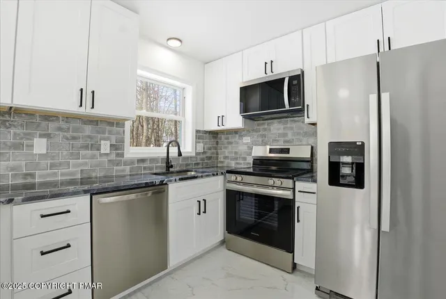 a kitchen with stainless steel appliances white cabinets and a stove top oven