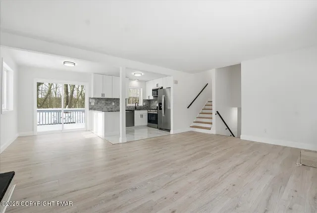 a view of an empty room with wooden floor and stairs