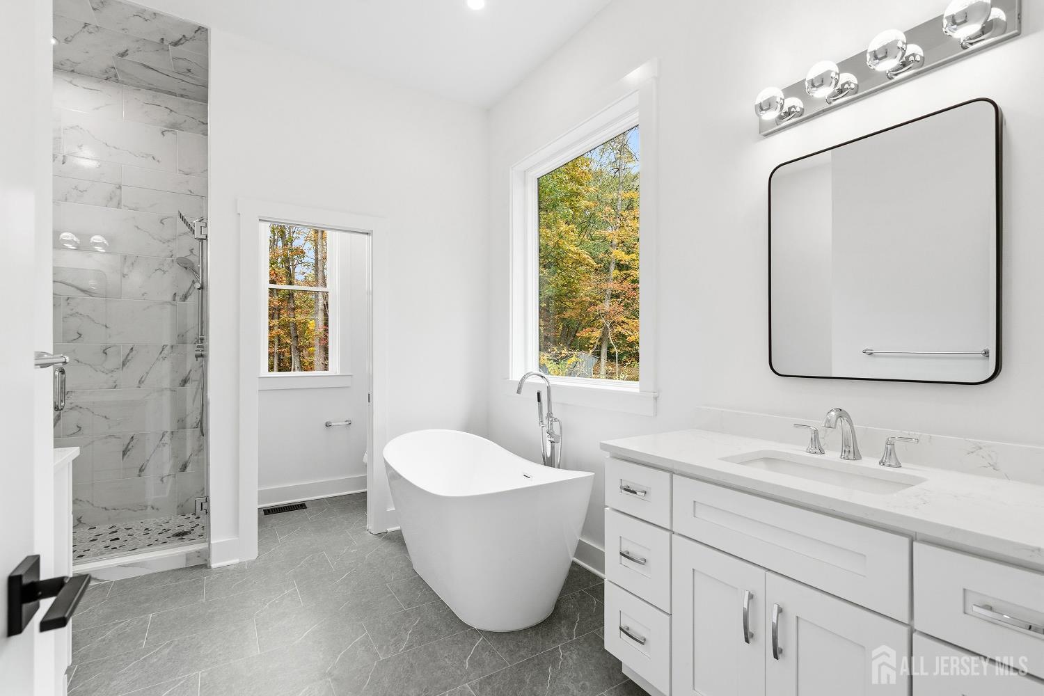 34 Mill Road Manalapan, NJ 07726 - Photo 13 of 30 a bathroom with a double vanity sink a mirror and a bathtub