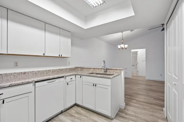a kitchen with granite countertop white cabinets and a sink