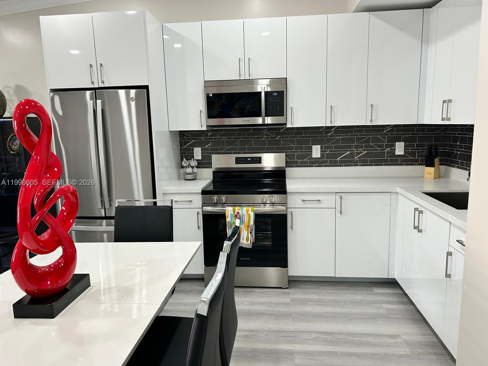 9922 Southwest 2nd Street, Unit A Miami, FL 33174 - Photo 10 of 24 a kitchen with stainless steel appliances a stove a sink and a refrigerator