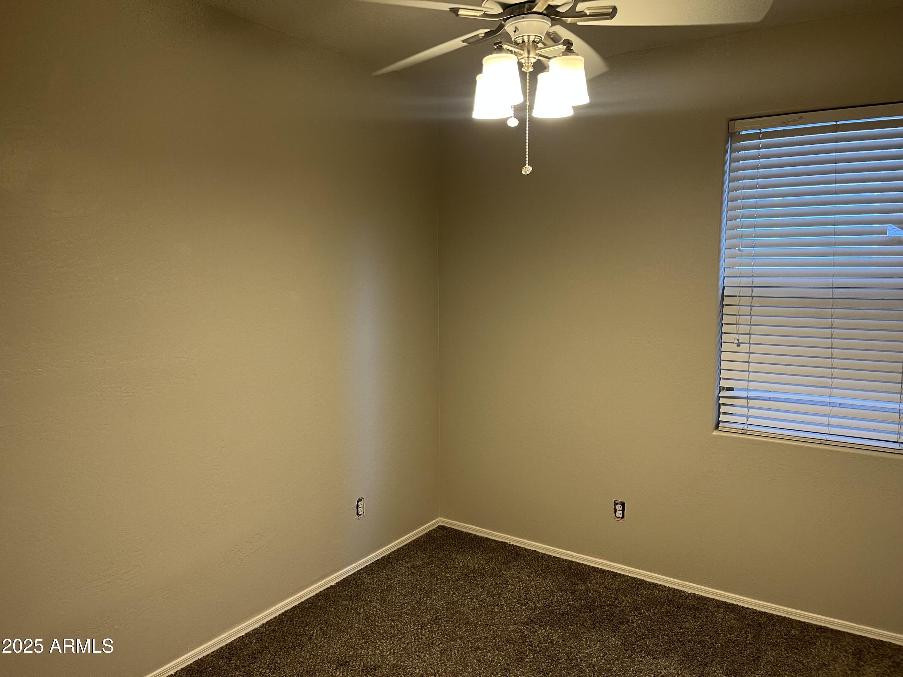 7007 West Carson Road Laveen, AZ 85339 - Photo 16 of 19 an empty room with a chandelier fan and a window