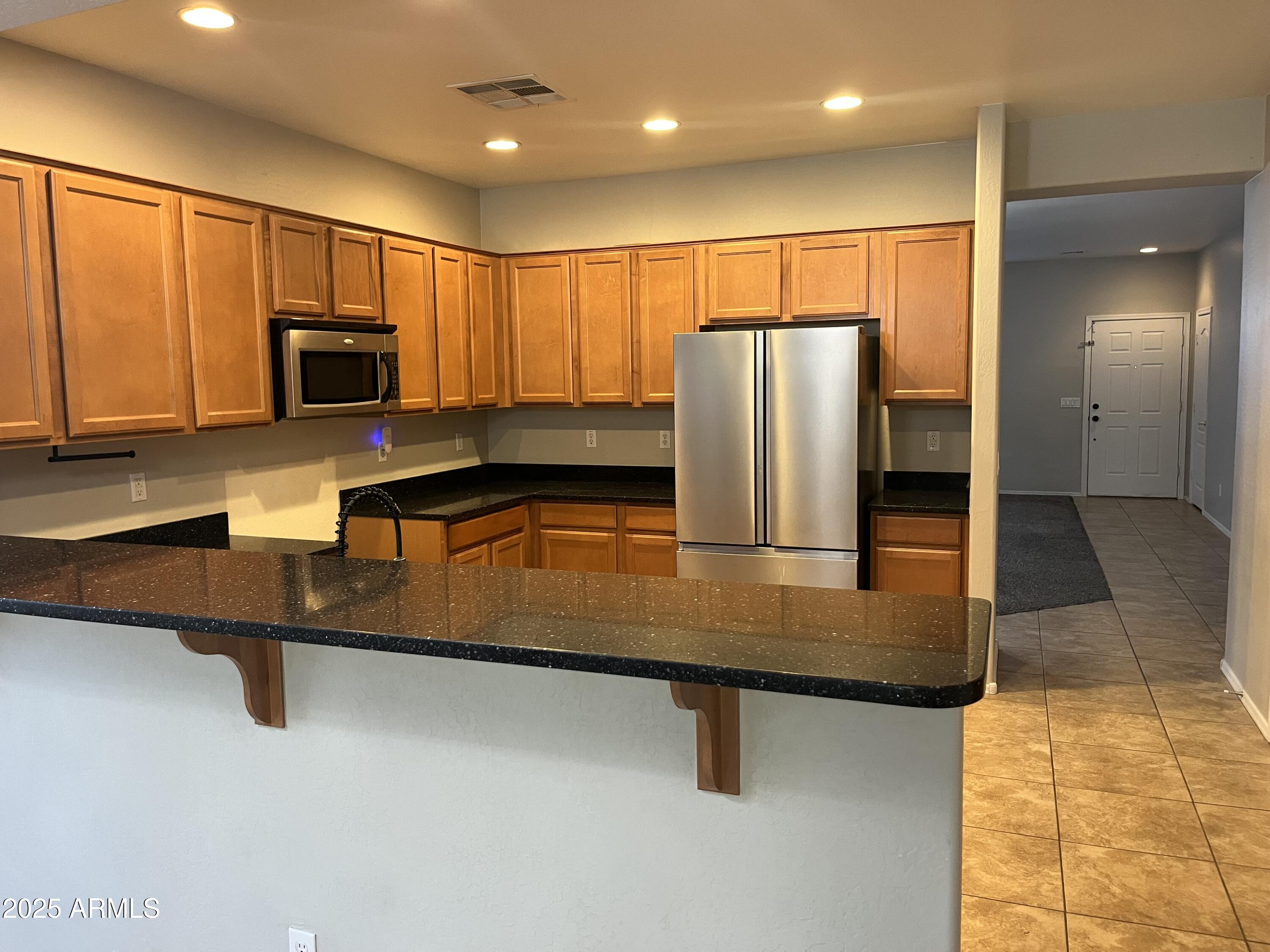 7007 West Carson Road Laveen, AZ 85339 - Photo 4 of 19 a kitchen with stainless steel appliances granite countertop a refrigerator a stove and a sink with wooden cabinets