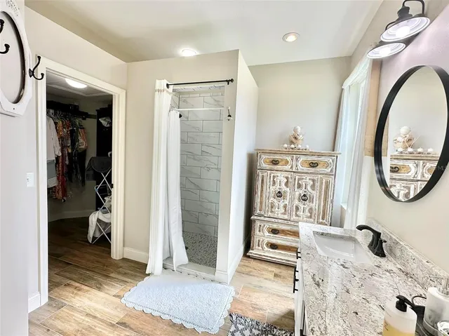 a bathroom with a granite countertop sink a mirror and shower