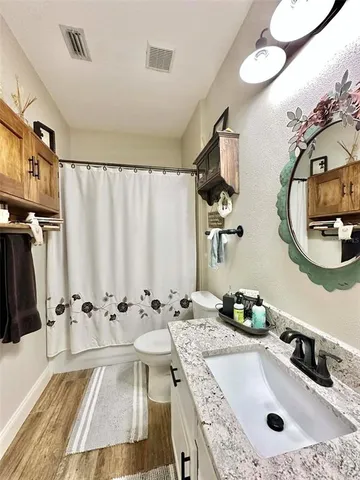 a bathroom with a granite countertop sink toilet and a mirror