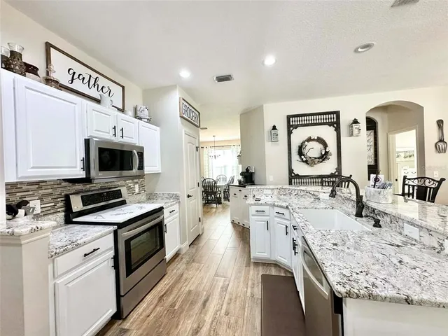 a large kitchen with stainless steel appliances granite countertop a lot of counter space and wooden floor