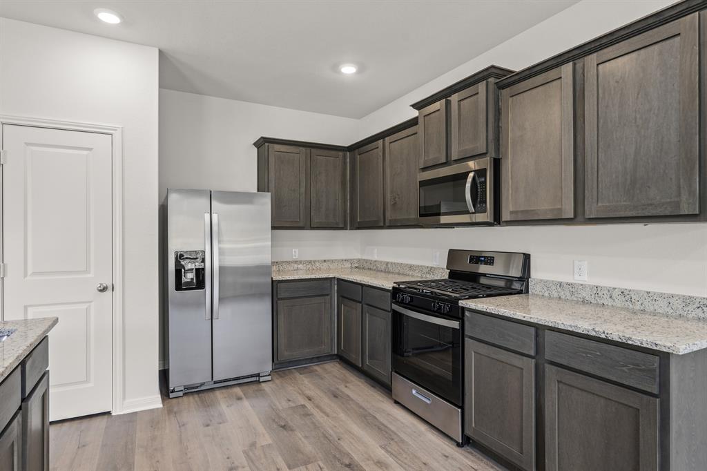 521-a D A D Crain Street Venus, TX 76084 - Photo 5 of 17 a kitchen with granite countertop a refrigerator a sink a stove a microwave and wooden cabinets