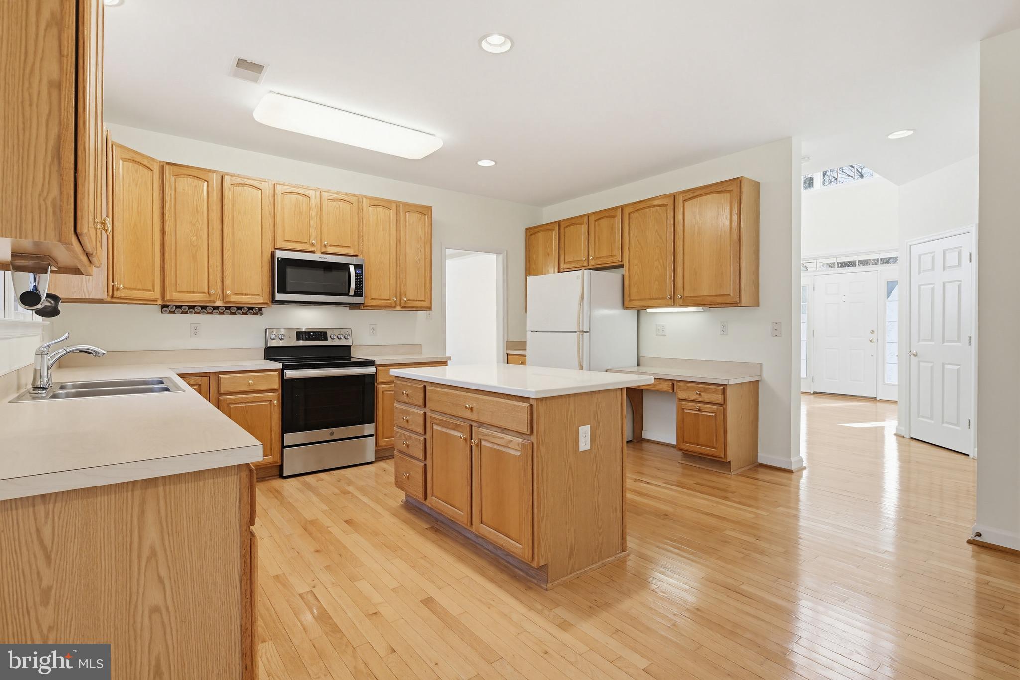 12017 Floating Clouds Path Clarksville, MD 21029 - Photo 26 of 54 a kitchen with kitchen island granite countertop wooden cabinets a stove a sink a refrigerator and a microwave