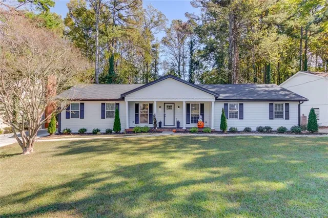 a front view of a house with a garden and trees
