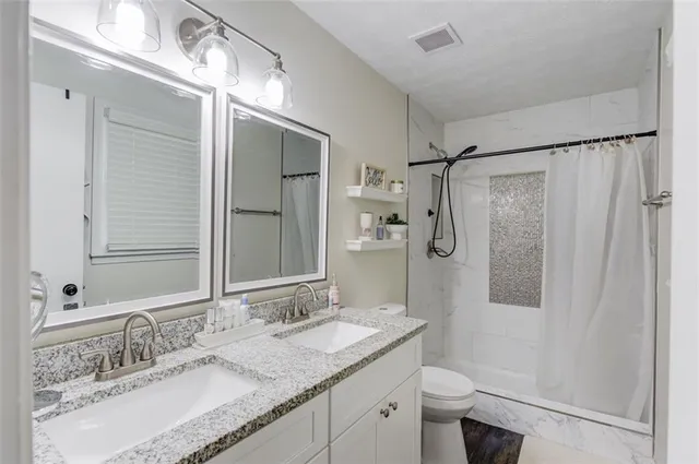 a bathroom with a granite countertop sink toilet and shower