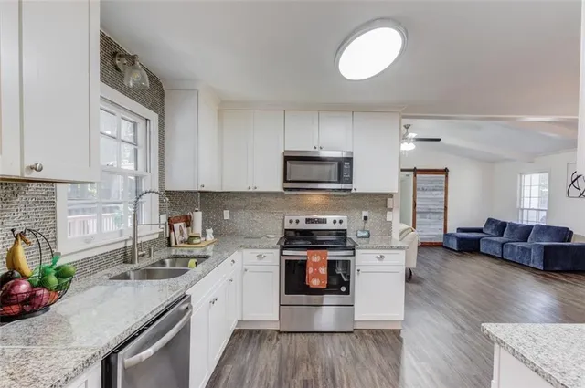 a kitchen with stainless steel appliances granite countertop wooden cabinets a stove a sink and a wooden floors