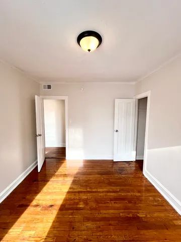 a view of an empty room with wooden floor and window