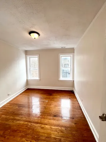 a view of an empty room with window and wooden floor