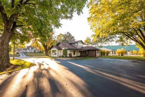 a view of a white house with a large tree