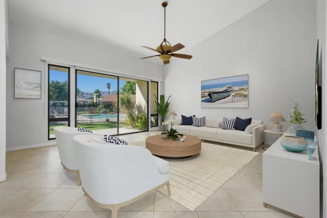 a living room with furniture a chandelier and a floor to ceiling window