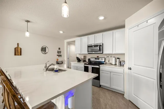 a kitchen with a sink a stove a refrigerator and white cabinets