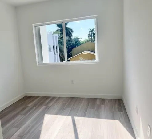 an empty room with wooden floor and a floor to ceiling window