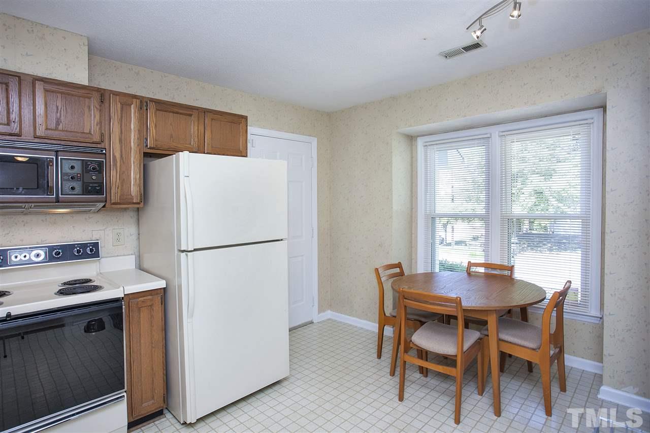 1500 Ferncliff Circle Raleigh, NC 27609 - Photo 10 of 25 a white kitchen with a stove a refrigerator and a dining table