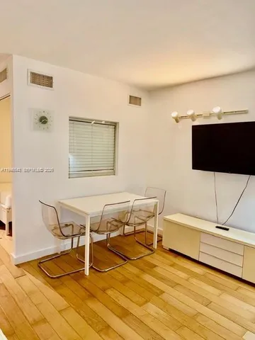 a living room with a table chairs and a flat screen tv