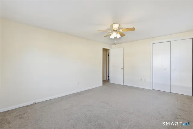 an empty room with closet and a ceiling fan
