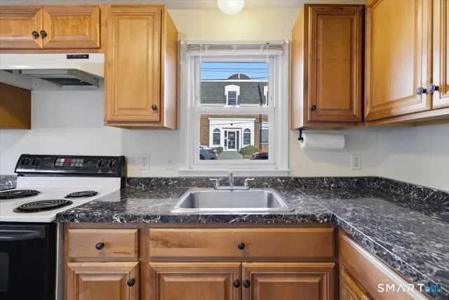 a kitchen with granite countertop a sink and a stove