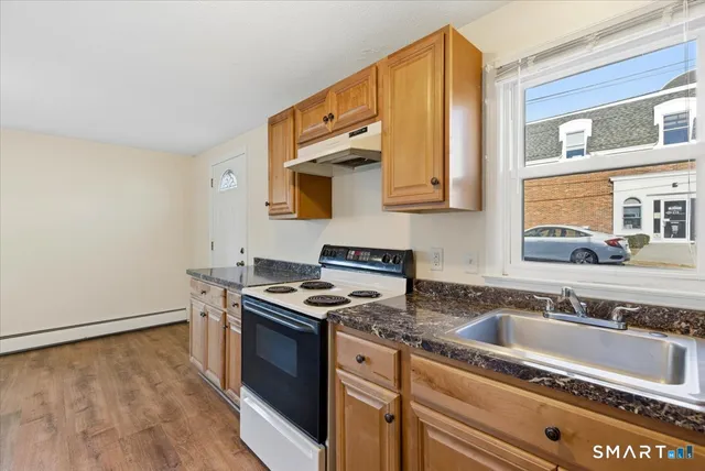 a kitchen with granite countertop a sink a stove and cabinets