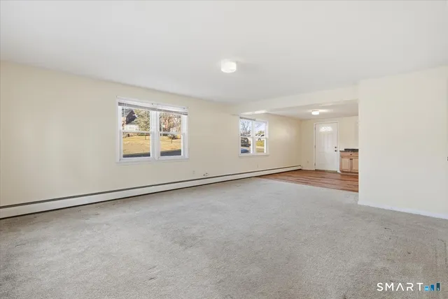 an empty room with windows and refrigerator