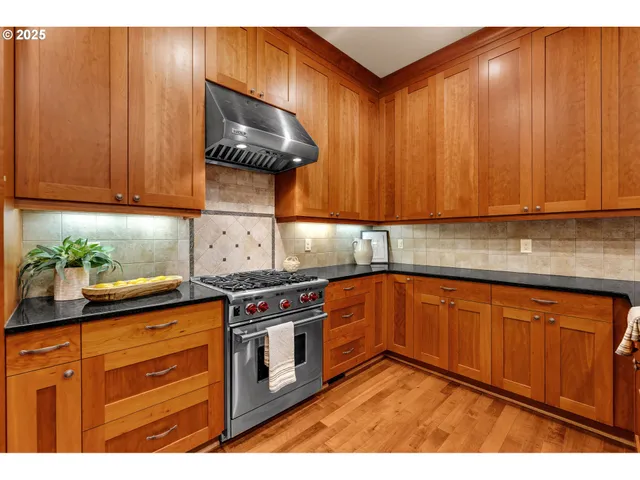 a kitchen with stainless steel appliances granite countertop wooden cabinets a stove and a sink