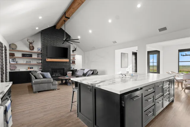 a living room with stainless steel appliances kitchen island granite countertop a stove and a sink