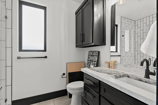 a bathroom with a granite countertop sink toilet and mirror