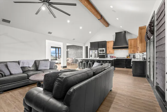 a living room with stainless steel appliances furniture and a kitchen view