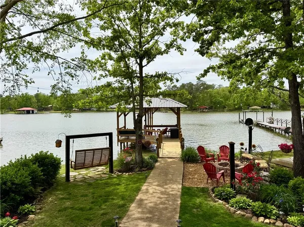 a view of a lake with table and chairs next to a yard